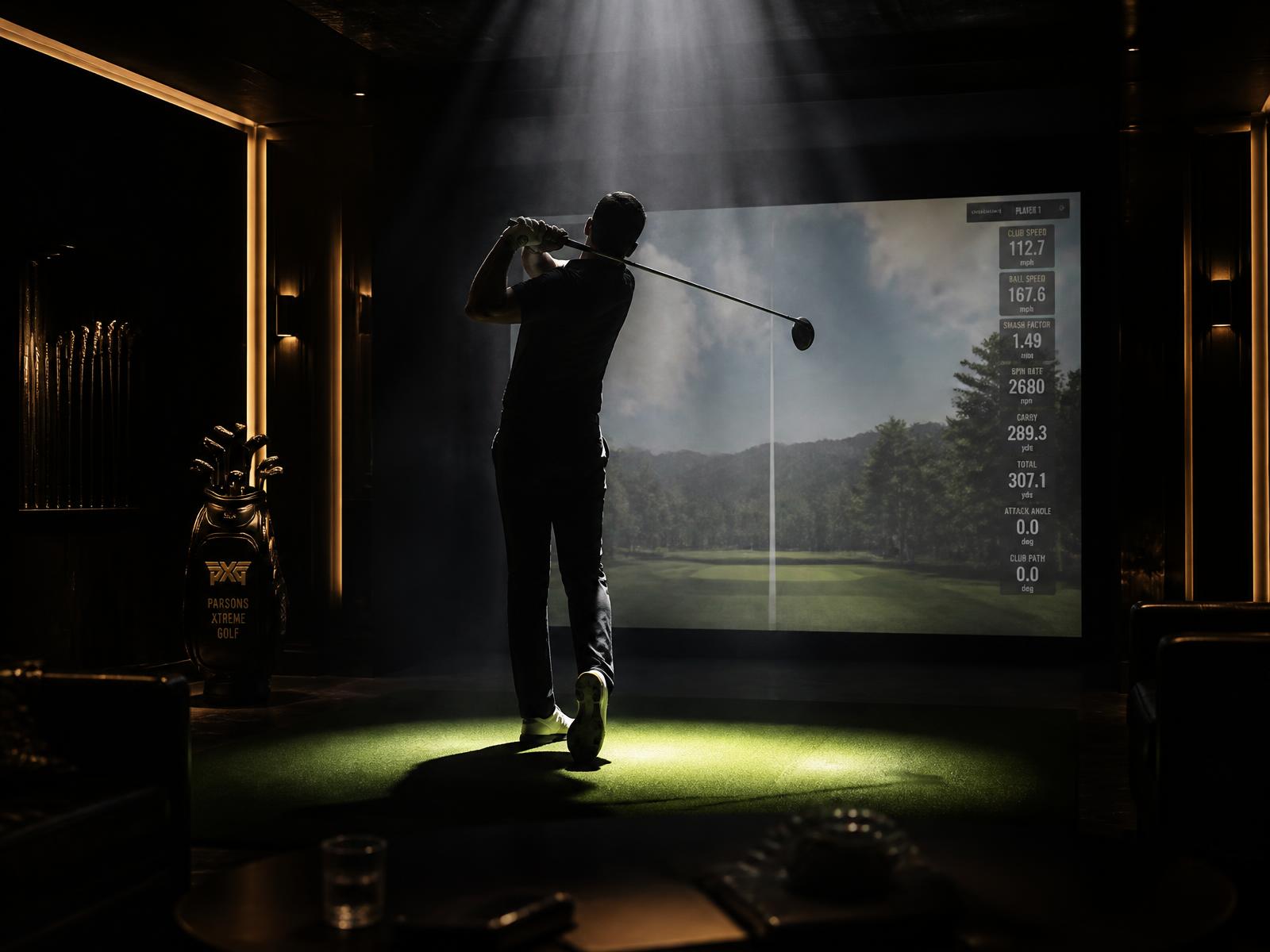 Golfer silhouetted in dramatic light taking a shot in a golf simulator